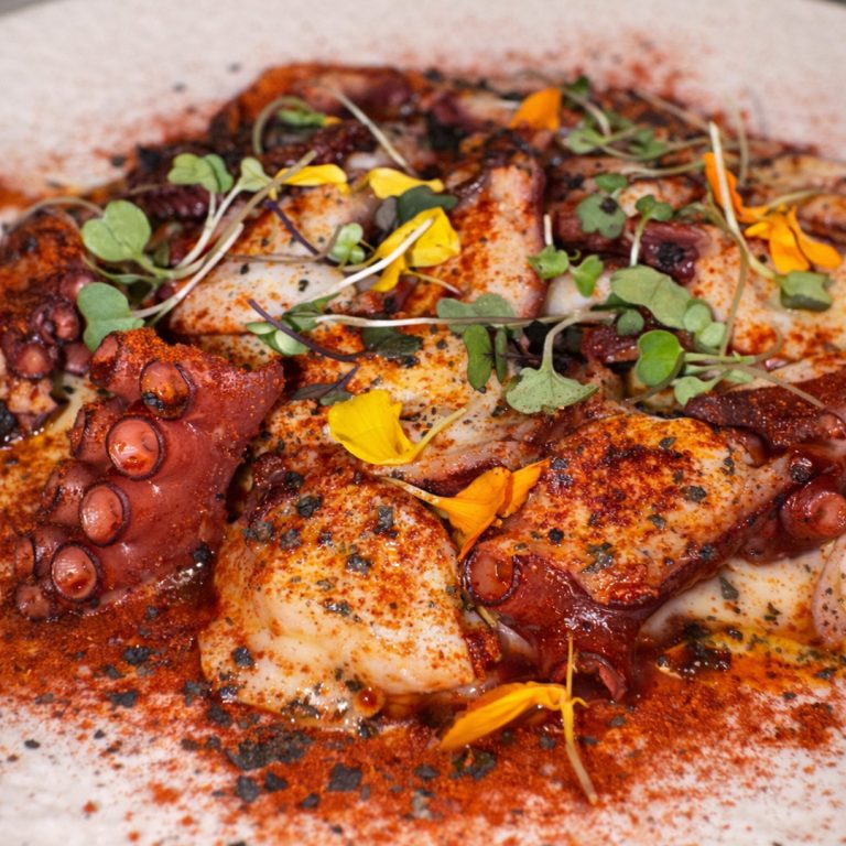 Pulpo a la brasa con cremoso de patata y ajo negro y pimentón de la Vera servido en Tolón Tolón Bilbao, asador especializado en producto a la parrilla.