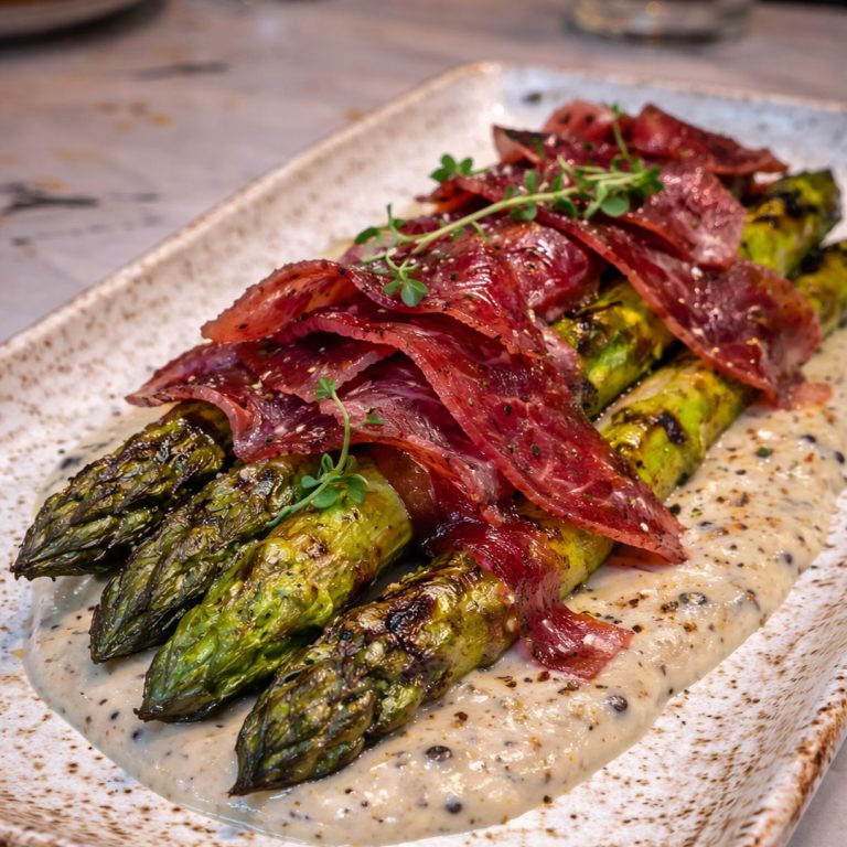 Espárragos a la brasa con crema trufada y virutas de cecina servidos en Tolón Tolón Bilbao, asador especializado en producto a la parrilla.